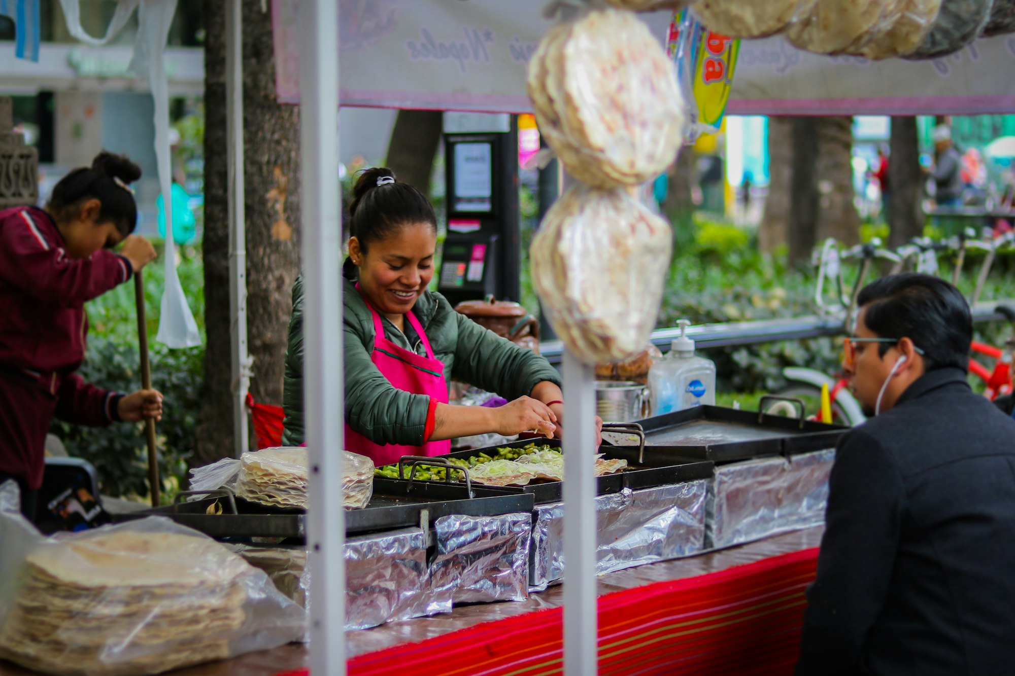 Street cook pressing fresh tortillas on a griddle